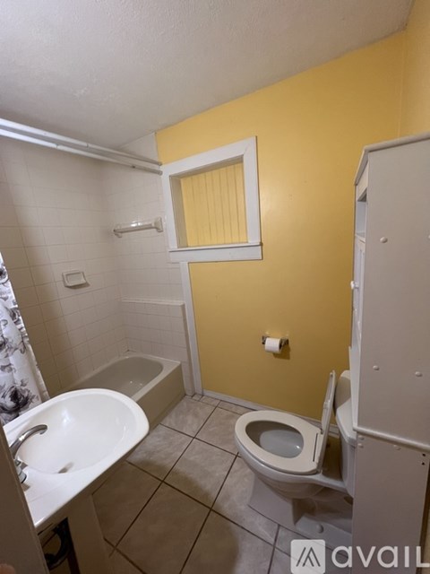 A bathroom with yellow walls has a toilet, sink, and bathtub.