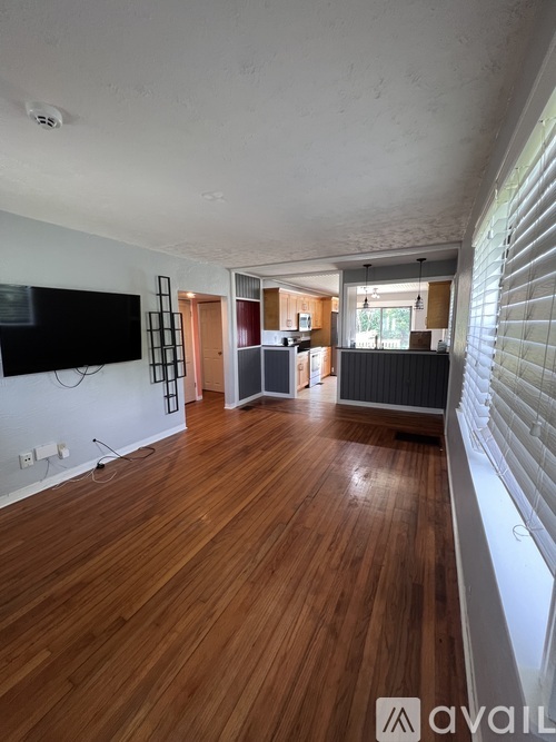 A living room with wooden floors and a television mounted on the wall.