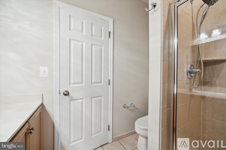 A white door is in a bathroom with a toilet and a walk in shower.