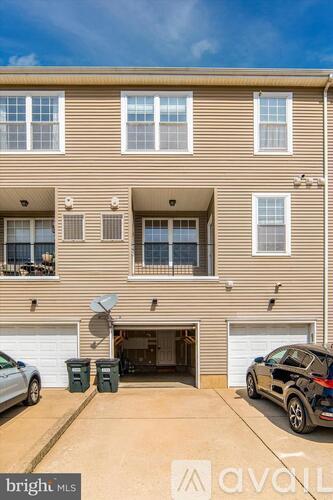 A two-story apartment building with a satellite dish on the roof and a car parked in the driveway.
