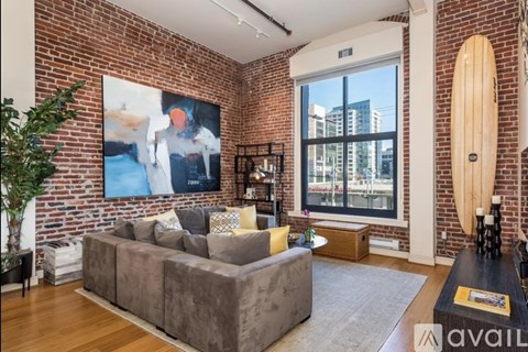 A living room with a grey couch and a large painting on the wall.