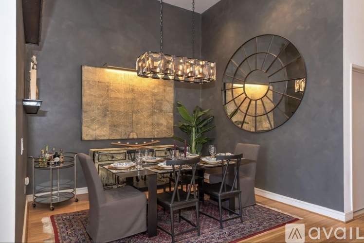 A dining room with a table set for four and a large circular mirror on the wall.