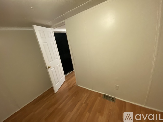A room with a white door and wooden floor.