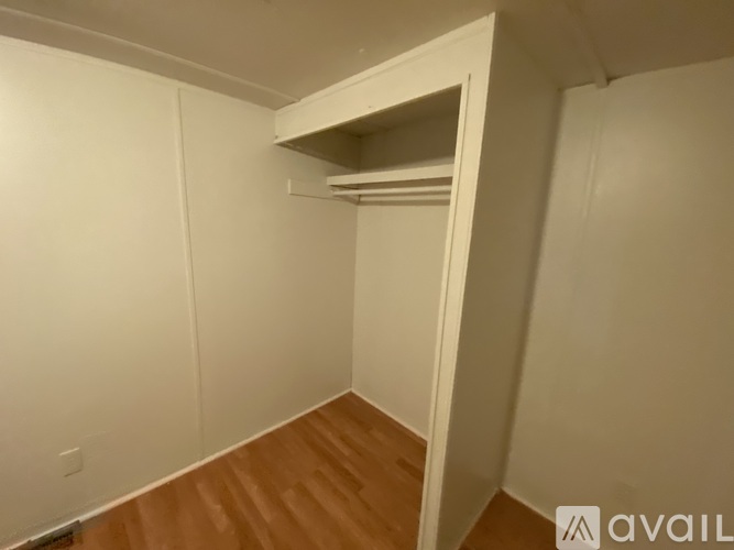 A small, empty room with a wooden floor and white walls.