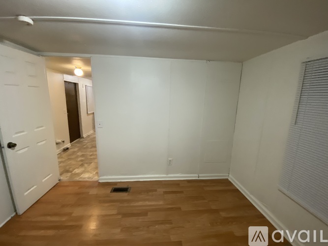 A room with wooden flooring and white walls.