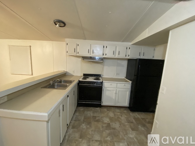 A kitchen with white cabinets and a black refrigerator.
