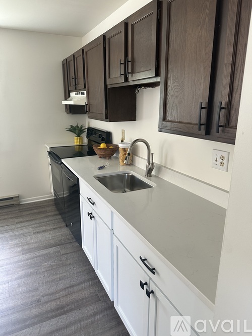 A kitchen with dark brown cabinets and a white sink.
