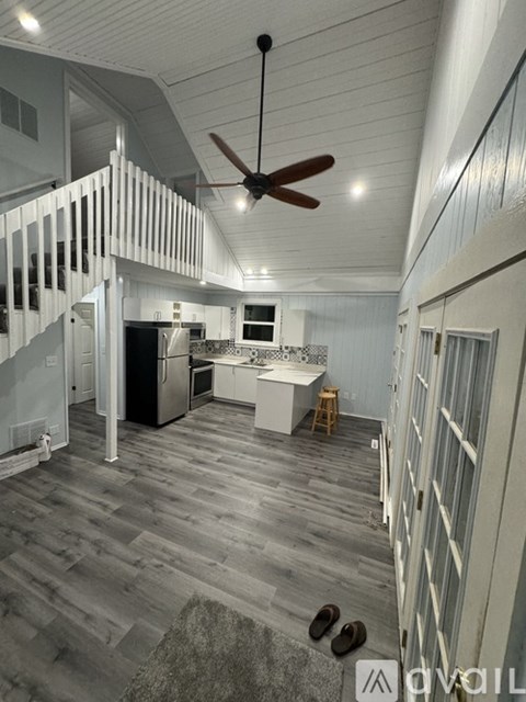 A modern kitchen with a wooden floor and a ceiling fan.