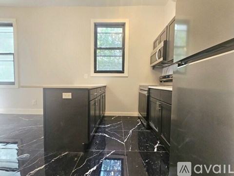 A kitchen with black cabinets and a marble floor.