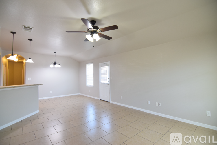 A spacious room with a ceiling fan and lighting fixtures.