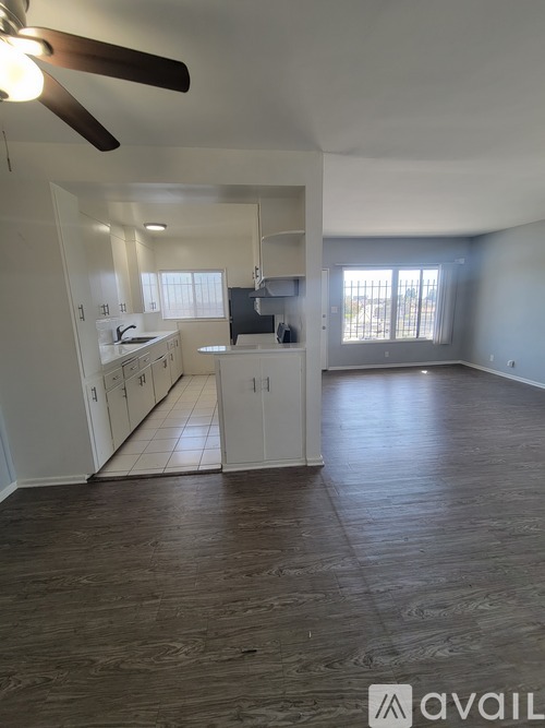 A spacious room with a ceiling fan and wooden flooring.