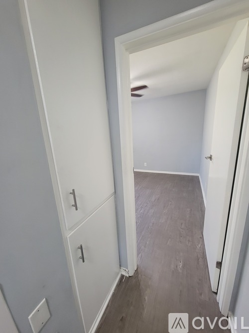 A hallway with a white door and a white cabinet with three drawers.