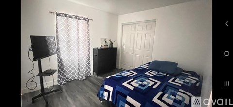 A bedroom with a bed, a chair, and a window with curtains.