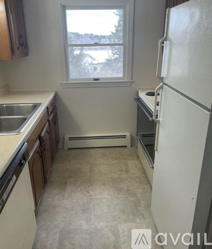 A kitchen with a white fridge and a window overlooking a snowy landscape.