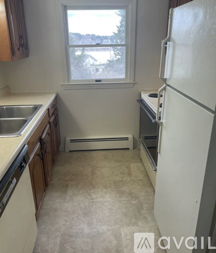 A kitchen with a white fridge and a window overlooking a snowy landscape.