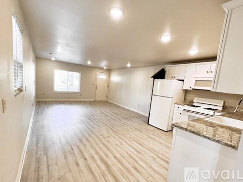 A kitchen with white cabinets and a wooden floor.