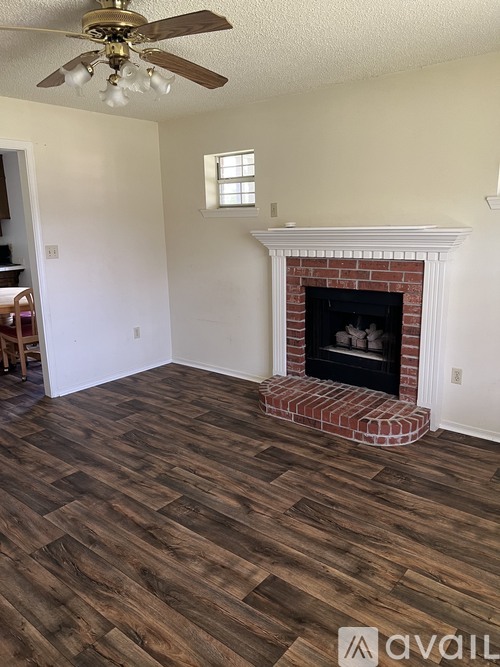 A room with a fireplace and wood flooring.