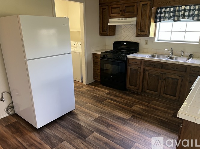 A kitchen with a white fridge, black stove, and wooden cabinets.