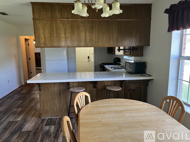 A kitchen with wooden cabinets and a table with chairs.