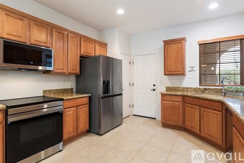 A kitchen with wooden cabinets and a black refrigerator.