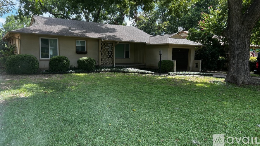 A house with a well-maintained lawn and trees in the background.