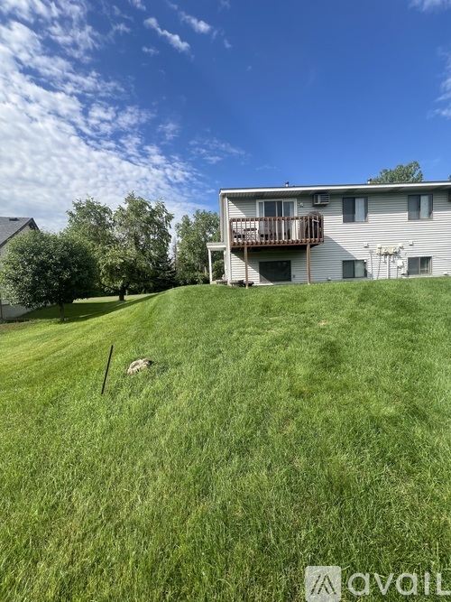 A grassy area in front of a house with a deck.