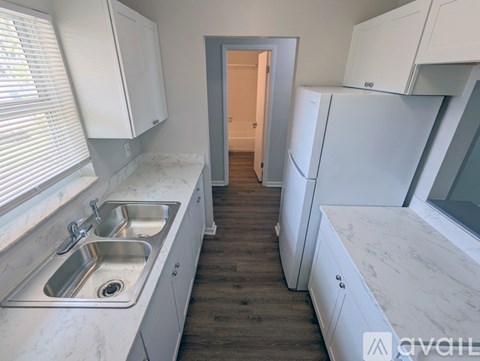 A kitchen with white cabinets and a marble countertop.