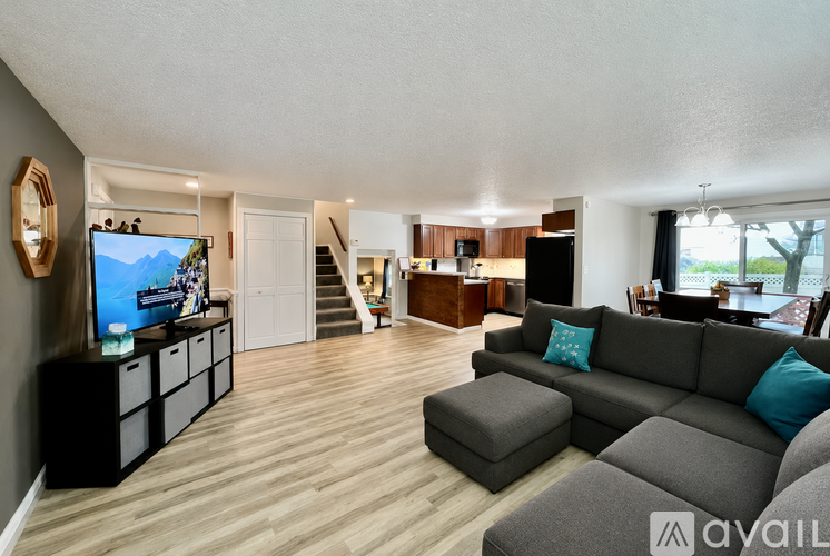 A living room with a grey couch and a television on the wall.