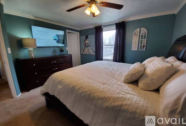 A bedroom with a bed, dresser, and ceiling fan.