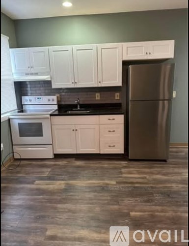 A kitchen with white cabinets and a stainless steel refrigerator.