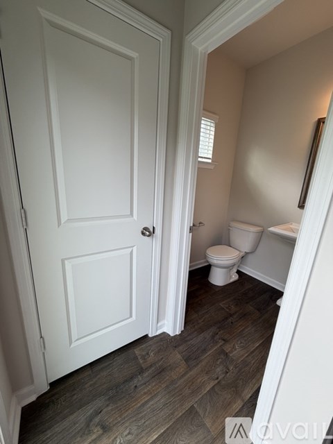 A white door is open to a small bathroom with a toilet and a sink.