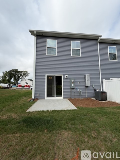 A grey house with a white fence and a green lawn in front.