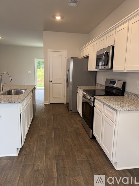 A kitchen with white cabinets and a black fridge.