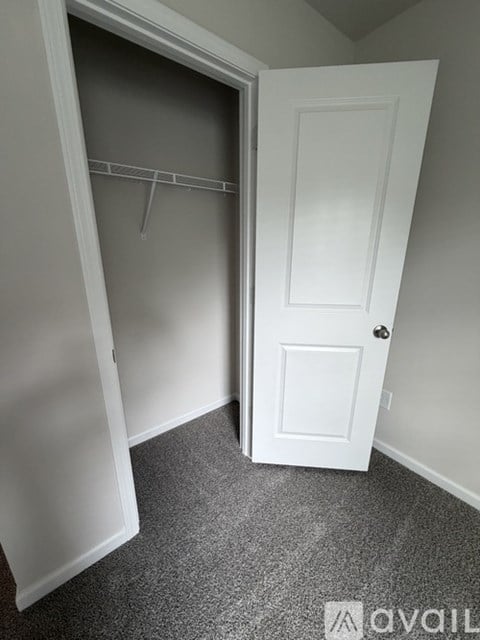 A white door is open to a room with a grey carpet.