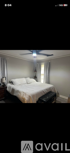 A bedroom with a bed, nightstand, and window.