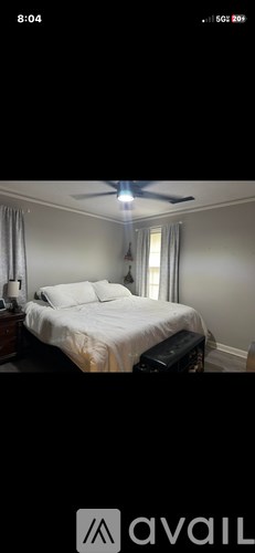 A bedroom with a bed, nightstand, and window.