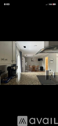 A kitchen with granite countertops and a dining area with a wooden table and chairs.