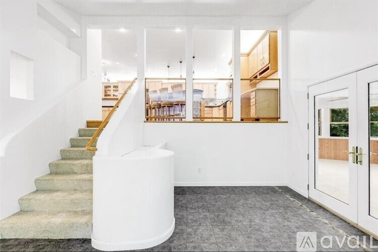 A white staircase with a yellow handrail leads to a living room with a couch and a coffee table.