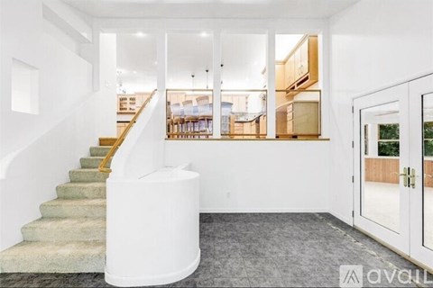 A white staircase with a yellow handrail leads to a living room with a couch and a coffee table.