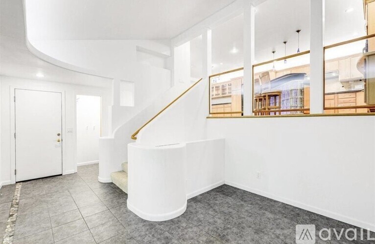 A spacious interior with a white staircase and a view of the outside through the windows.
