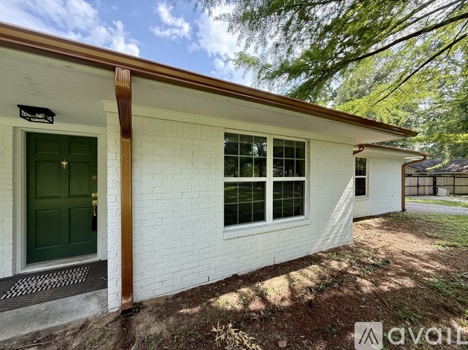 A white house with a green door and a brown roof.