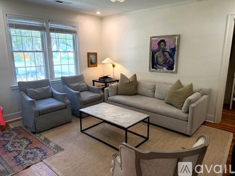 A living room with a grey couch, a coffee table, and a painting on the wall.