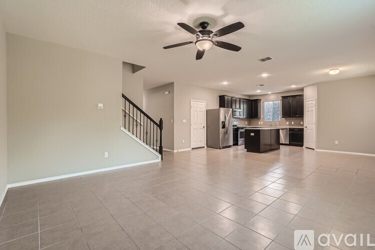 A spacious living room with a ceiling fan and tiled flooring.