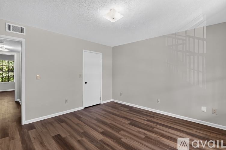 A room with a white door and a window with a view of trees.