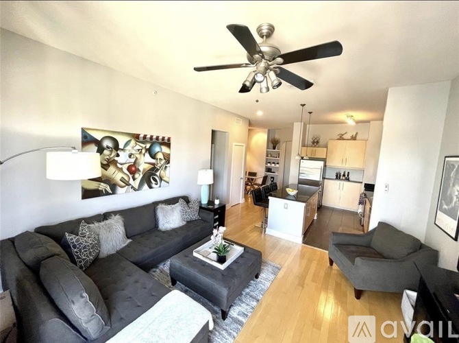 A living room with a grey couch and a ceiling fan.