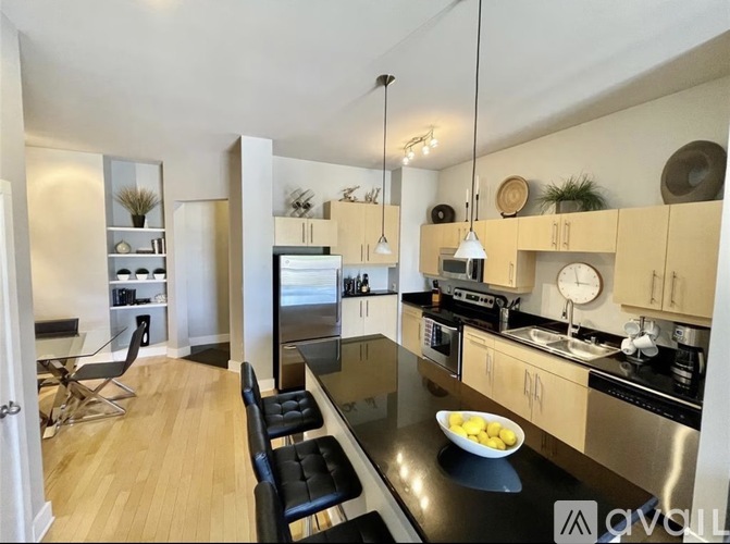 A modern kitchen with a black countertop and stainless steel appliances.