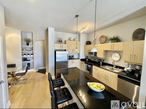 A modern kitchen with a black countertop and stainless steel appliances.