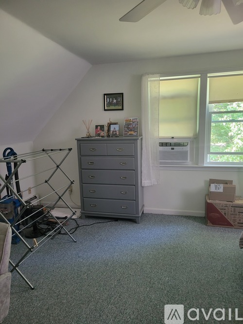 A room with a grey dresser and a window with blinds.