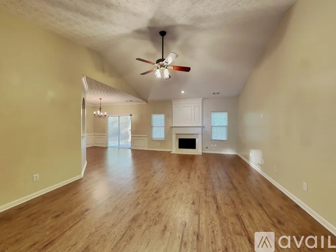 A spacious room with a ceiling fan and hardwood floors.