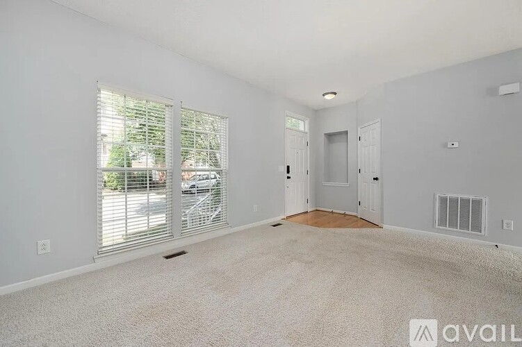 A spacious room with a carpeted floor and a sliding glass door leading to a balcony.